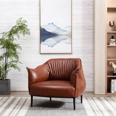 a brown leather chair sitting in front of a book shelf next to a potted plant