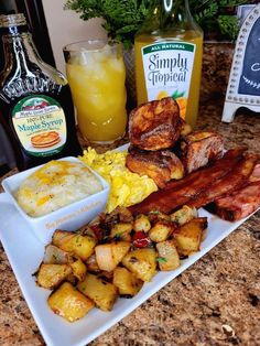 the breakfast is ready to be eaten on the kitchen counter with eggs, bacon, potatoes and orange juice