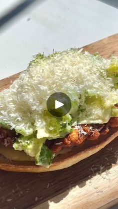 an open faced sandwich with lettuce and cheese on it sitting on a cutting board