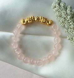 Brazilian Rose Quartz with Double S999 Silver, Gold Plated Pixiu and Chinese Coin Ball Charm Bracelet   Bead Size: 8mm (approx) S999 Silver, Gold Plated Pixiu Size: L17.5 x W9 x H8mm (approx)  ✅ All stones are unique and may vary from the one shown in the picture ✅ All Stones will be selected at random from our stock. ✅ Please kindly do note & to accept before any purchase.  Rose Quartz is a stone of love that helps to open the heart and connect to the energy of love. Rose Quartz is pure and upl Pixiu Bracelet, Chinese Coin, Bracelet Bead, Mythical Creature, Attract Wealth, Bead Charm Bracelet, Love Rose, Feng Shui, Rose Quartz