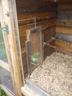 the inside of a chicken coop that is made out of wooden planks and wood shavings