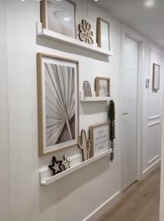 a hallway with white walls and pictures on the wall, along with wooden flooring