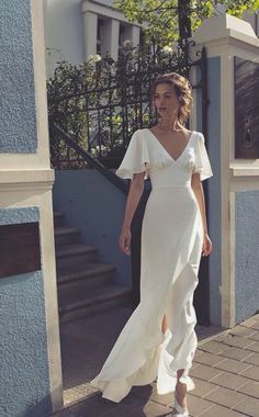 a woman in a white dress is walking down the street