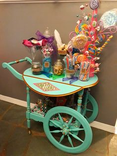 an old fashioned cart with candy and candies on the top is sitting in front of a wall