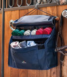 a bag hanging on the side of a wooden door with several different items in it