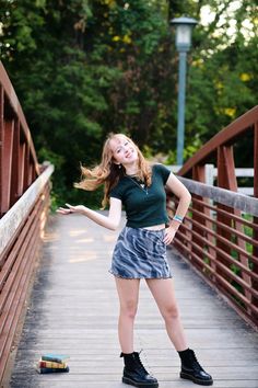 a woman is standing on a bridge with her arms spread out and she's smiling