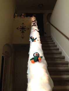 there are stuffed penguins on top of the white fluffy pole next to the stair case