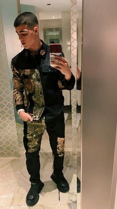 a young man taking a selfie in a mirror wearing camouflage pants and black shoes