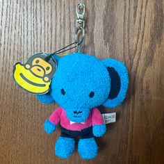 a blue stuffed animal keychain with a smiley face on it's chest