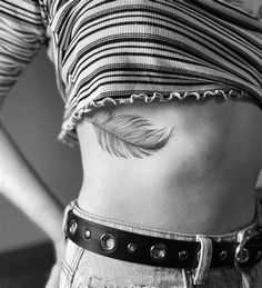 a woman's stomach with a feather tattoo on her belly and the bottom part of her waist