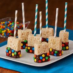 rice krispy treats are arranged on a plate with candy and lollipop sticks