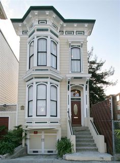 a large white house sitting on the corner of a street with stairs leading up to it