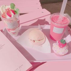 a pink tray topped with two ice creams and a sandwich next to a drink