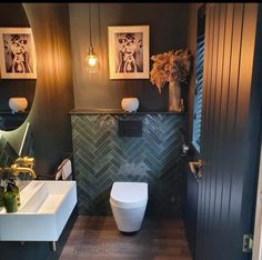 a bathroom with two pictures on the wall and a toilet next to it in front of a mirror