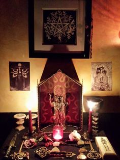 an altar with candles, pictures and other items on it in front of a painting