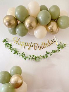 balloons and greenery are arranged in front of a happy birthday banner