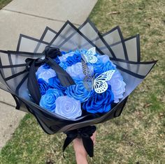 a woman holding a bouquet of blue roses in her hand with a butterfly on it