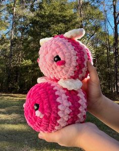 two crocheted stuffed animals sitting on top of each other in front of trees