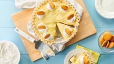 there is a pie on the table next to some plates and bowls with desserts