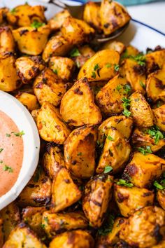 a platter filled with roasted potatoes and dipping sauce on the side, ready to be eaten