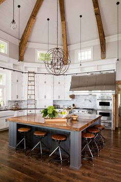 a large kitchen island with stools in the center and an oven on the other side