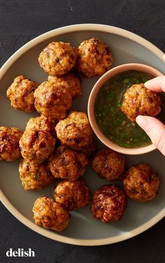 a person dipping sauce on some meatballs