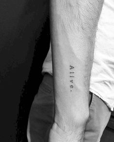 a man's arm with the word alive tattooed on his left forearm, in black ink