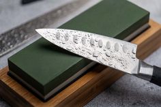 a knife sitting on top of a wooden block next to a green book and knife