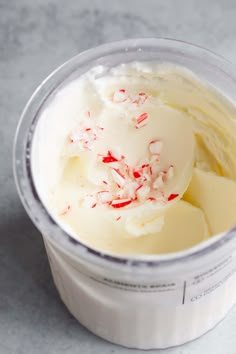 a plastic cup filled with ice cream and candy canes on top of a table