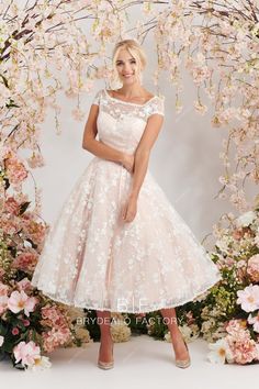 a woman standing in front of flowers wearing a white dress