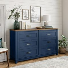 a blue dresser in a white room with pictures on the wall