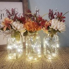 three mason jar vases with lights in them