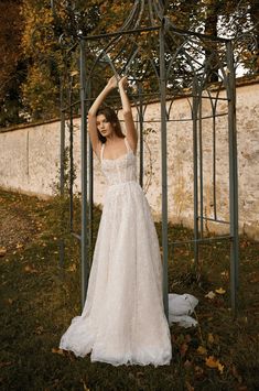 a woman in a white wedding dress standing under a gazebo with her arms up