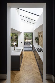 an open kitchen with wooden floors and white counter tops, along with a skylight