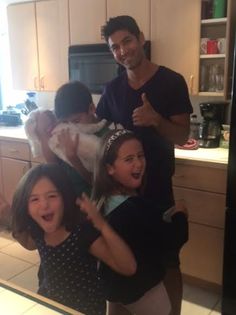 a group of people standing in front of a kitchen counter with one woman holding a baby