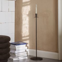 a stack of books sitting on top of a wooden floor next to a tall candle