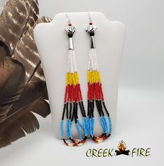 These are authentic Native American earrings, hand crafted by a member of the Muskogee Creek Tribe. Used in the handmade process are seed beads and buffalo charm. The bead colors included in this pair are: black, silver, white, yellow, red, and blue seed beads. They measure 1/2 inch wide and 6 inches long (6 1/2 including the ear wire). They have silver plated ear wires for pierced ears. Native American Beaded Earrings Fire Mountain Gems And Beads, Beaded Earrings Native Fire Mountain Gems And Beads, Native Anerican Earrings, Native American Beaded Earrings Inspire Uplift ⭐, Southwestern Style Multicolor Nickel-free Beaded Earrings, Blue Beaded Earrings, Seed Bead Crafts, Bead Loom Designs, Native American Earrings