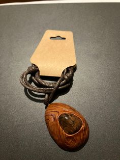 a wooden object with a tag attached to it sitting on a table next to a cord