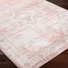 an antique style rug with faded pink and white colors on a wooden floor in a living room