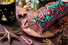 a chocolate christmas roll with candy canes and candies on a wooden platter