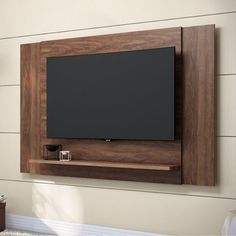 a flat screen tv mounted to the side of a wall with wooden shelves on it