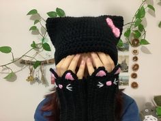 a woman covering her face with black knitted cat gloves