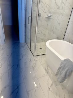 a white bath tub sitting next to a walk in shower and a glass enclosed shower door