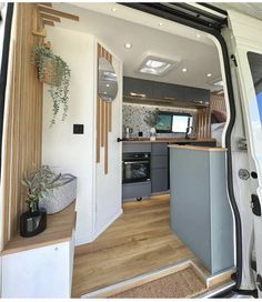 the interior of a camper van with its door open and plants in pots on the counter