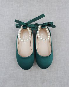 a pair of green shoes with pearls tied to them