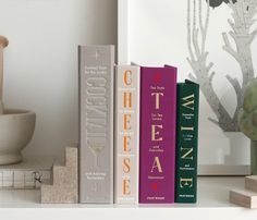 three books are sitting on a shelf next to a vase