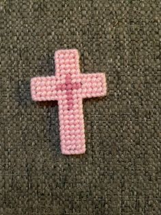 a pink crocheted cross laying on the ground