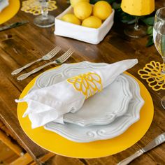 a yellow and white place setting with lemons in the background