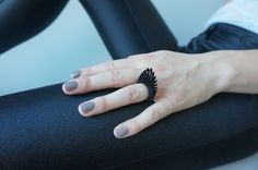 a woman's hand on top of a chair with her nails painted in black