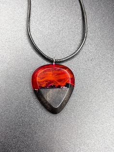 a red and black glass pendant on a silver surface